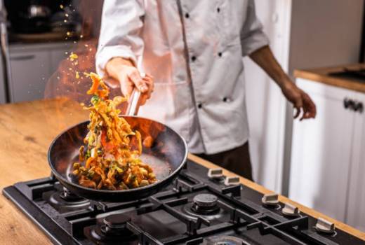 a chef cooking food in a flaming pan