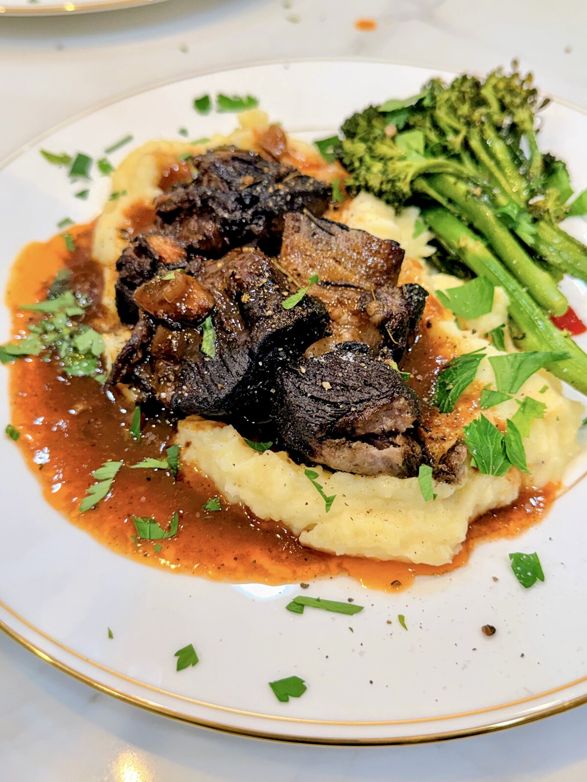 Braised short rib over mashed potatoes with broccolini, plated by a Travelling Cafe chef