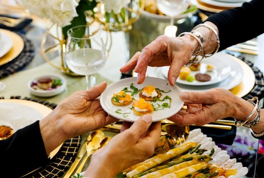 Guests passing plates across a dinner party table set by The Travelling Cafe