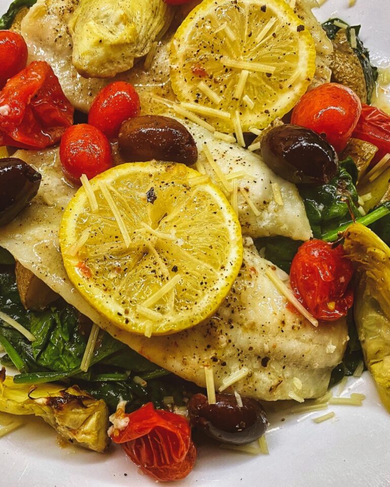 Lemon fish over spinach with roasted tomatoes, olives and artichokes, made by a Travelling Cafe chef
