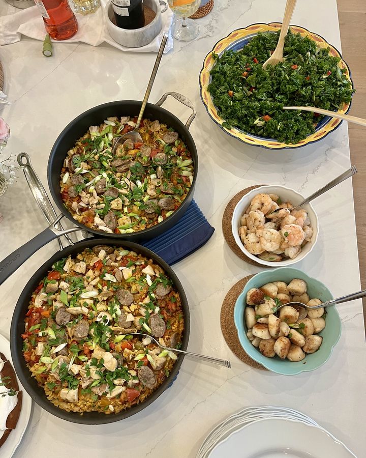 Two pans of paella with sides for a vacation group