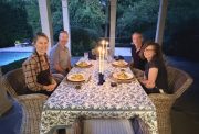 Four guests sharing dinner at a candlelit outdoor table at dusk